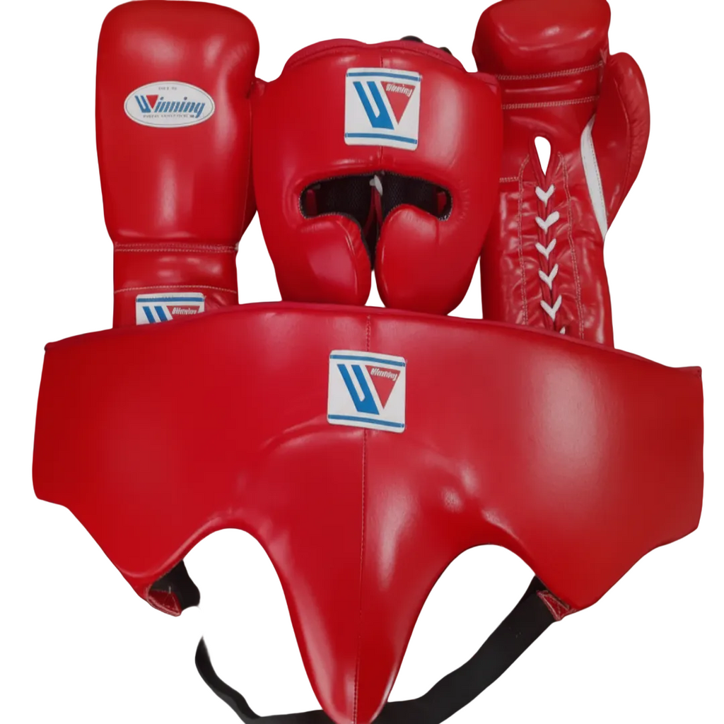 A set of red boxing gear including a headguard, boxing gloves, and a mouthguard, all featuring the Winning brand logo, displayed against a dark background.