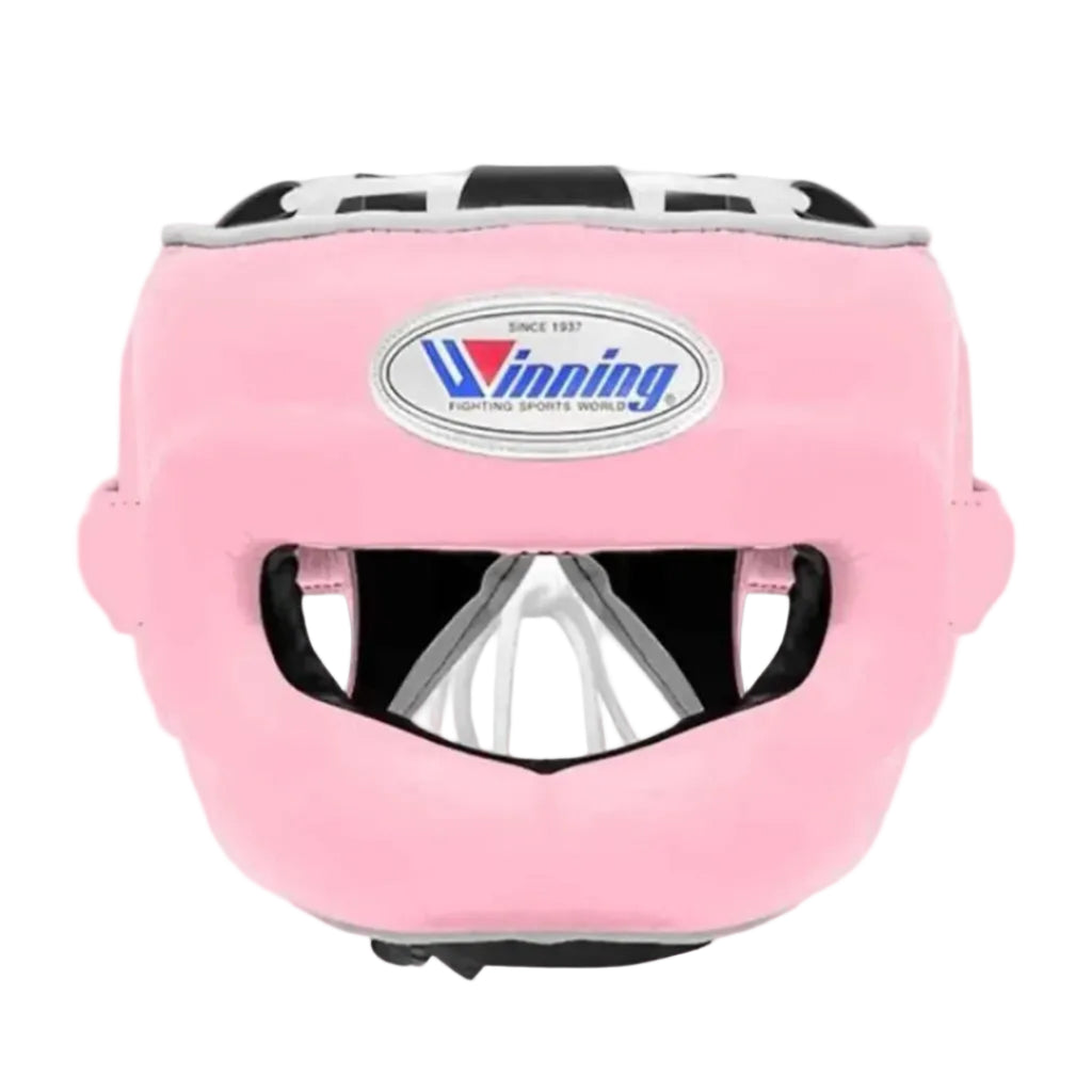 Pink martial arts headgear with a clear face guard and a visible Winning logo on the forehead, shown against a neutral gray gradient background.