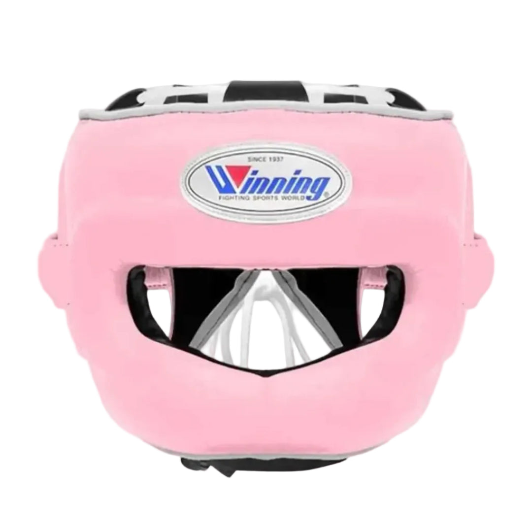 Pink martial arts headgear with a clear face guard and a visible Winning logo on the forehead, shown against a neutral gray gradient background.