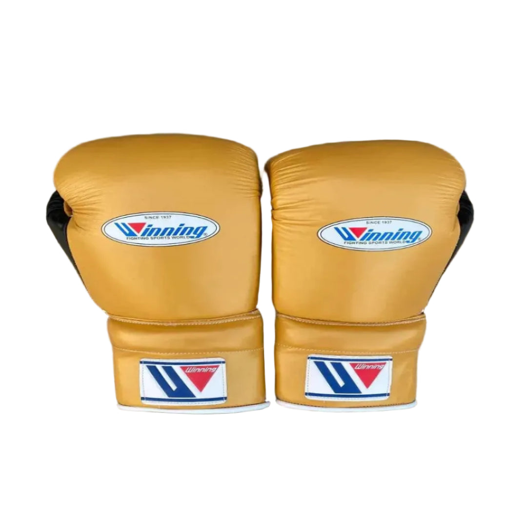 A pair of gold boxing gloves with white and blue Vinning brand patches, displayed on a dark wood background.
