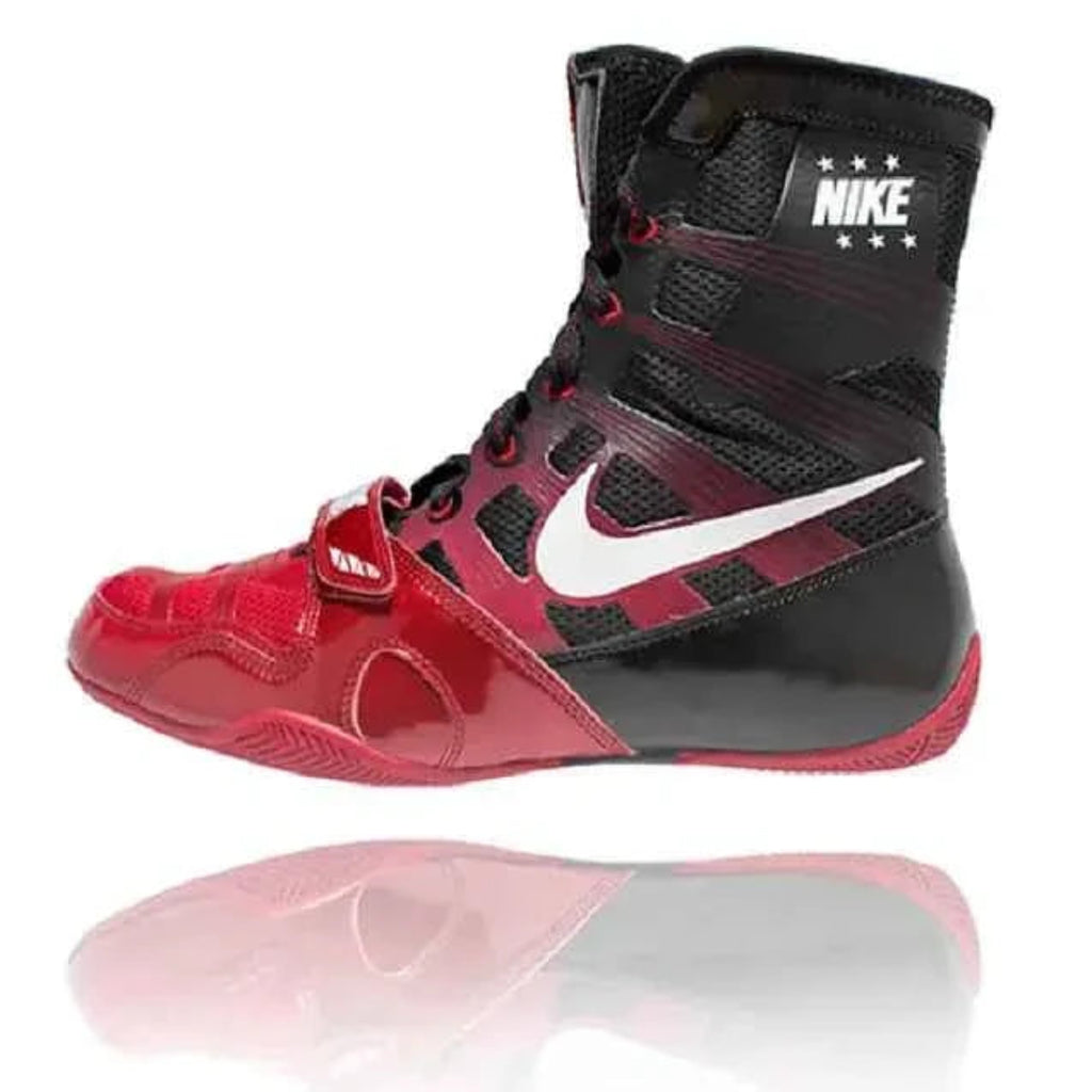 A Nike high-top athletic boot in black and red with a white Swoosh logo, shown in profile against a white background with a soft reflection below.