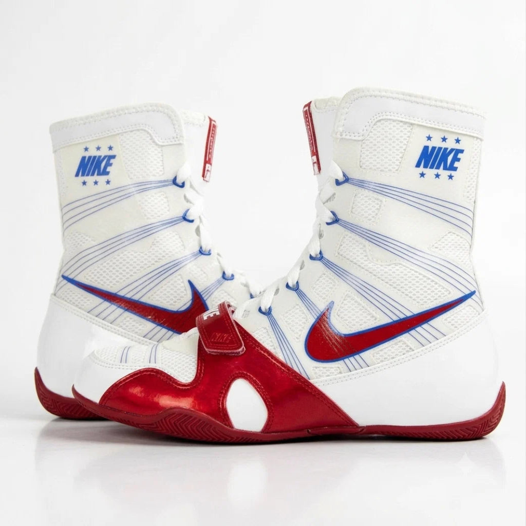A pair of white high-top boxing shoes with red and blue accents, featuring the Nike Swoosh and Nike branding on a clean white background.