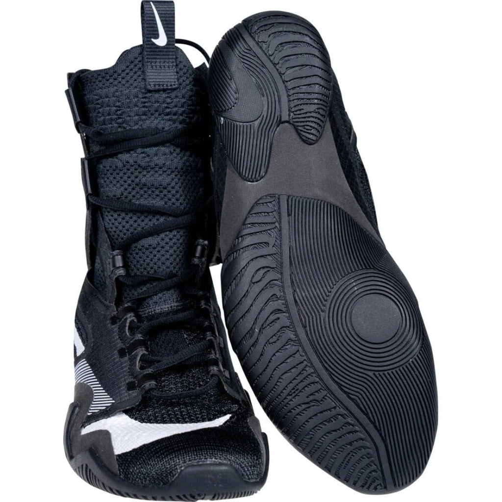 A pair of black high-top athletic sneakers shown on a white background, with one shoe standing upright and the other lying on its side to display the textured black outsole.